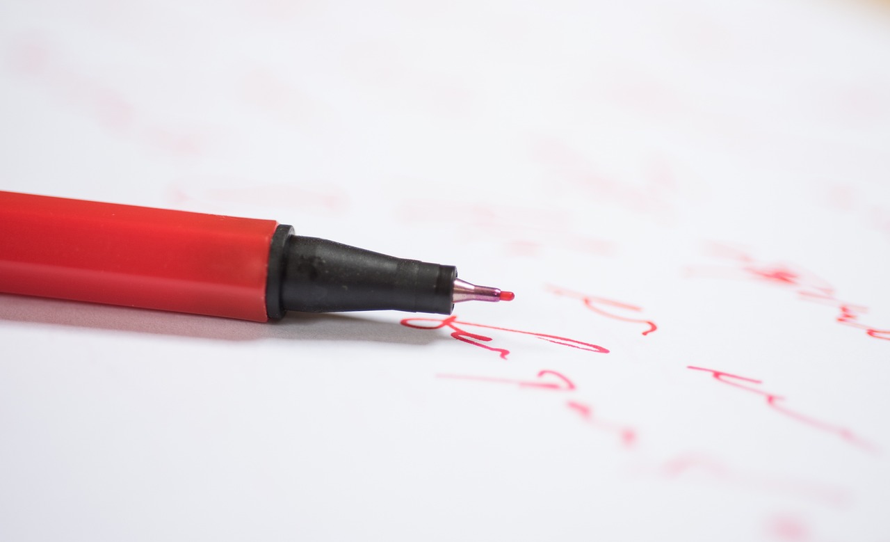 白い紙の上に置かれた赤いペン